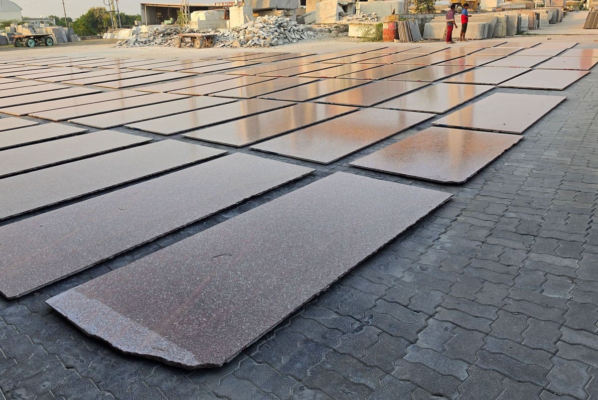 Polished red granite slabs laid out flat in the open yard